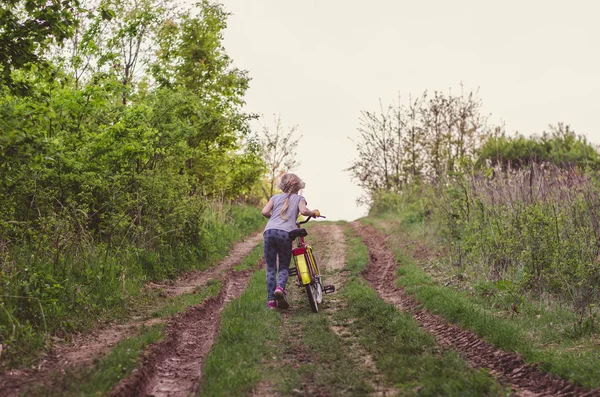 Kleines Kind schiebt Fahrrad auf dem Feldweg — Stockfoto