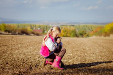 Kırsaldaki tarlada kedi yavrusu besleyen çocuk.