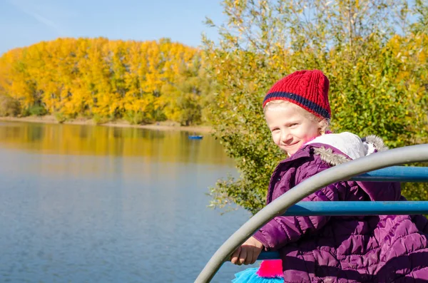 Mooi meisje in speeltuin in de buurt vijver in de herfst gouden uur tijd — Stockfoto