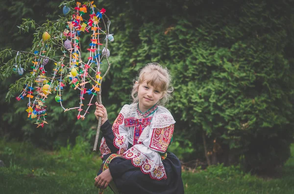 Easter traditional folk costume complimenting on Easter with colorful eggs hang on green branch — Stock fotografie