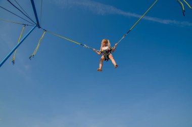 Sevimli genç kız, mavi gökyüzünde sallanırken bungee jumping cazibesinden hoşlanıyor.