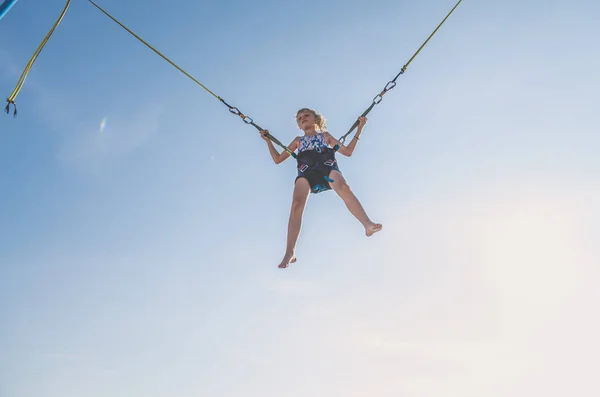 アクティブな若いですティーン女の子ジャンプでトランポリン高に青い空に安全なです弾性安全ベルト — ストック写真