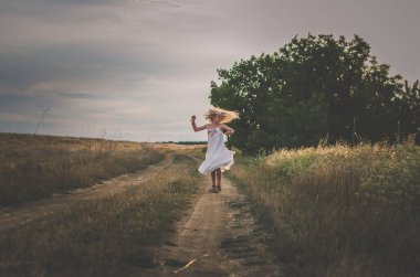 Uzun sarı saçlı kız yaz zamanı dans ediyor kırsal kesimde dramatik bir etki yaratıyor.