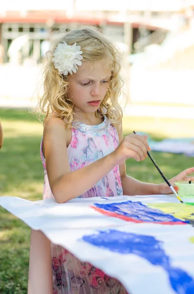 adorable child enjoying time outside while painting with colors