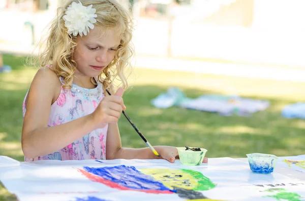 adorable child enjoying time outside while painting with colors