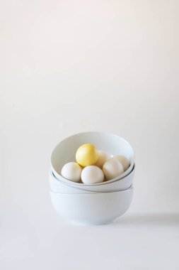 Stack of white bowls with white eggs on white background