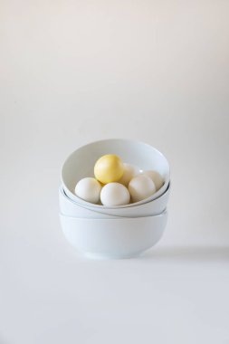 Stack of white bowls with white eggs on white background