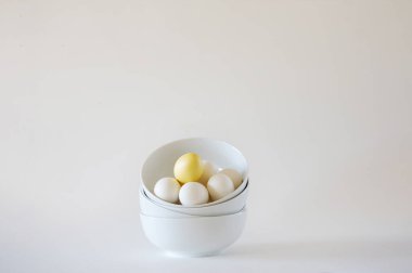 Stack of white bowls with white eggs on white background