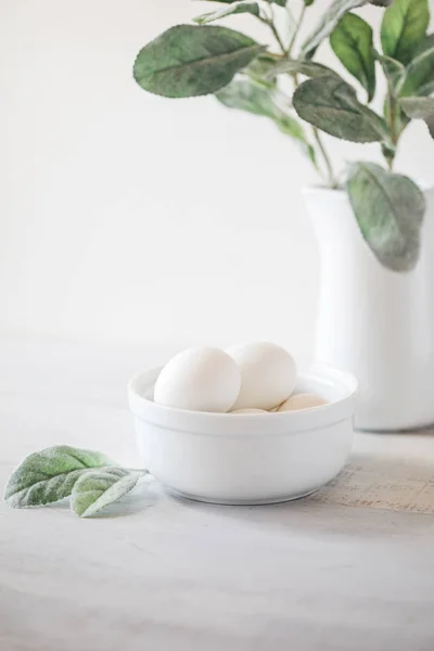 Kendi putih dengan tanaman bijak, mangkuk putih dengan telur di backgro putih — Stok Foto