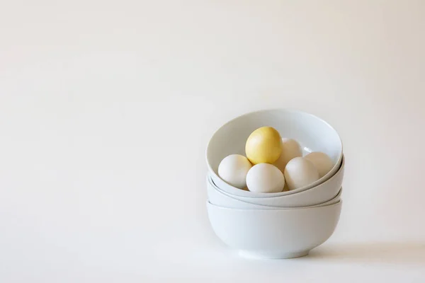 Stack of white bowls with white eggs on white background