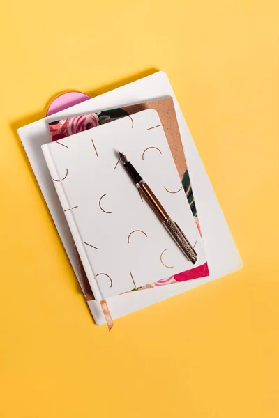Sarı arkaplan üzerine mürekkep kalemli ve kopya alanlı üç defter. Günlük yazma ve not alma kavramı.