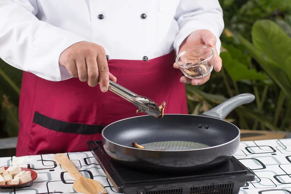 Chef mettant des champignons dans la casserole — Photo