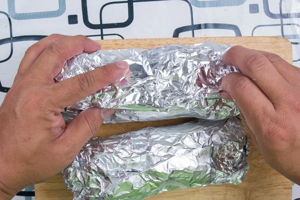 Envelopper le pain à la saucisse avec du papier aluminium — Photo