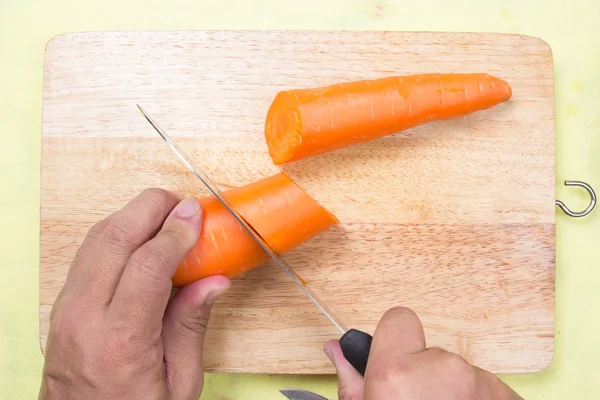 Chef cutting carrot on a wooden board — Stock Photo, Image