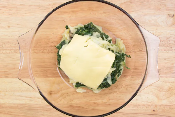 Putting cheese to spinach bowl