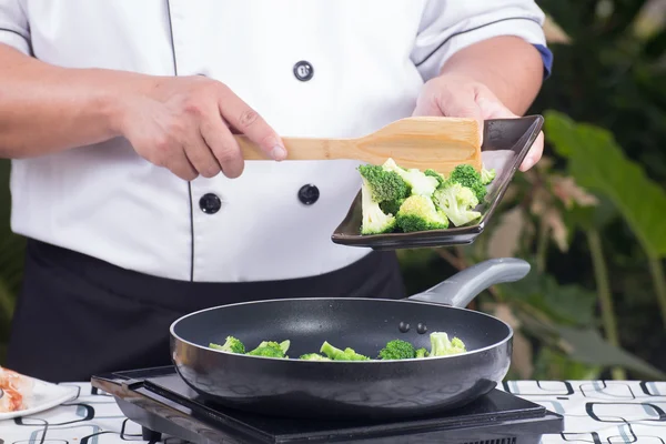 Chef putting broccoli to pan — Stockfoto