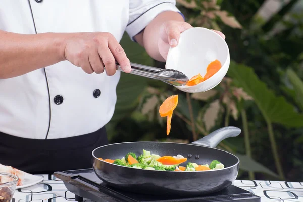 Koch gibt Karotte in die Pfanne — Stockfoto