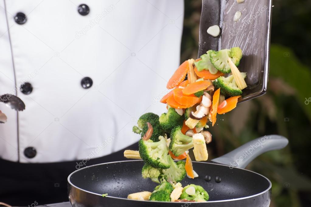 Chef putting vegetable to pan 