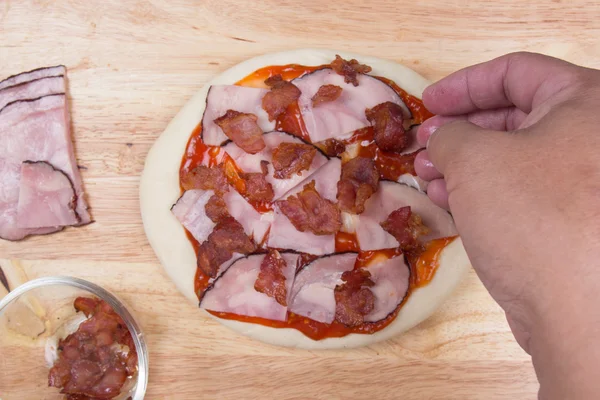 Putting Bacon on pizza crust — Stock Photo, Image