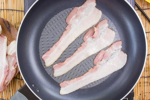 Chef frying bacon in the pan
