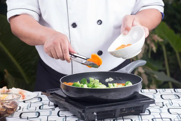 Шеф-повар кладет морковку на сковороду — стоковое фото