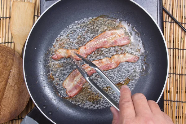 Chef-kok frituren spek in de pan — Stockfoto