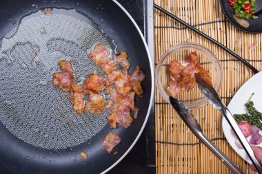 Şef gevrek domuz pastırması kupasına maşa tarafından tutarak.