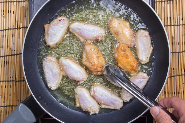 Chef-kok frituren Kippenvleugels in de pan — Stockfoto