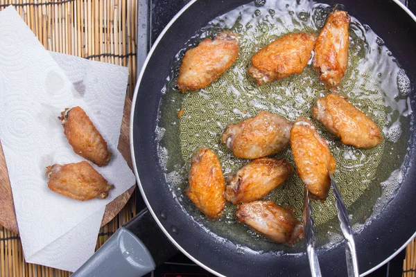 Chef-kok frituren Kippenvleugels in de pan Stockfoto