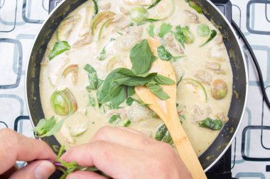 Yeşil köri yemek pişirmek için Tay fesleğen koyarak Şef