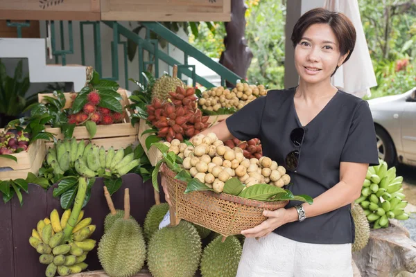 Aziatische vrouw met tropische fruitmand Stockafbeelding