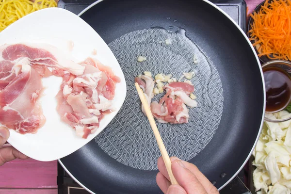 Шеф-повар кладет кусок свинины для приготовления Якисоба — стоковое фото