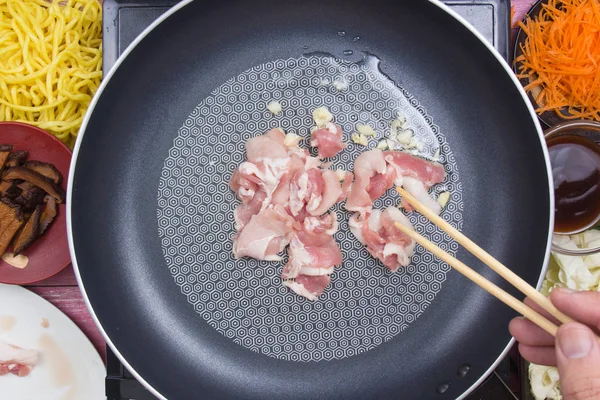 Шеф-повар помешивает жареный кусок свинины в кастрюлю — стоковое фото