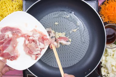 Şef Yakisoba yemek için domuz eti dilim koyarak