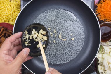 Şef Yakisoba yemek pişirmek için kıyılmış sarımsak koyarak