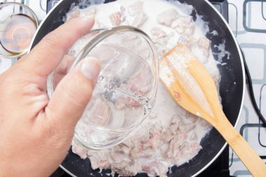 Şef yeşil yemek pişirmek için su dökerek köri