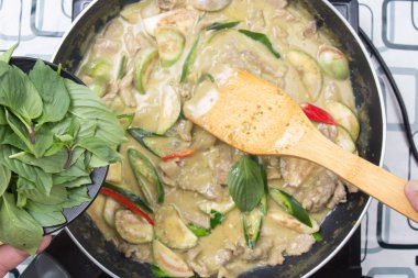 Yeşil köri yemek pişirmek için Tay fesleğen koyarak Şef