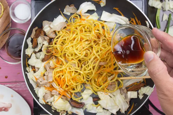 Şef soya sosu Yakisoba noodle yemek pişirmek için dökme