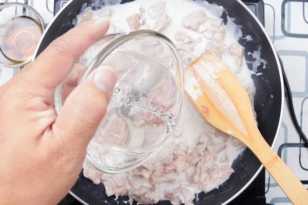 Şef yeşil yemek pişirmek için su dökerek köri