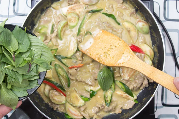 Yeşil köri yemek pişirmek için Tay fesleğen koyarak Şef