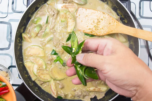 Yeşil köri yemek pişirmek için biber koyarak Şef