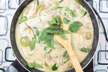 Yeşil köri yemek pişirmek için Tay fesleğen koyarak Şef