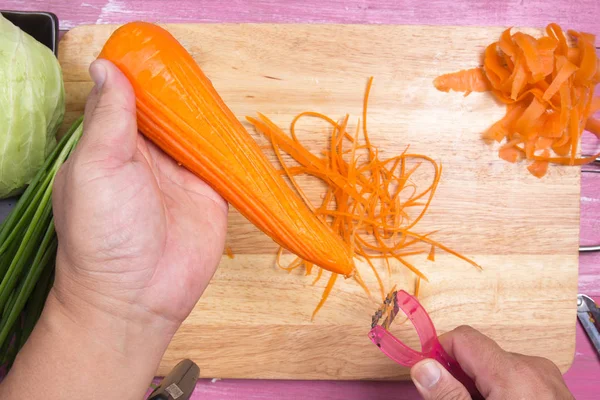 Kuchař oloupeme a nakrájíme mrkev — Stock fotografie