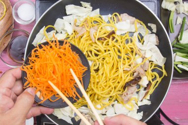 Şef Yakisoba noodle yemek pişirmek için havuç dilim koymak