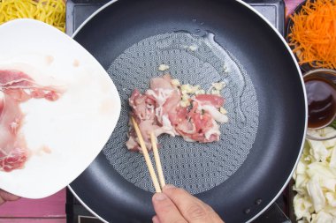 Şef Yakisoba pişirme / Yakisoba (Japanesed kızarmış şehriye) kavramı yemek için domuz eti dilim koyarak