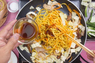 Şef Yakisoba makarna pişirme / Yakisoba (Fried Japon şehriye) kavramı yemek için istiridye sosu dökerek