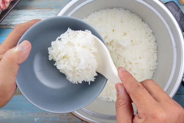 Arroz cocido en cucharón de plástico en olla de arroz eléctrica —  Fotos de Stock