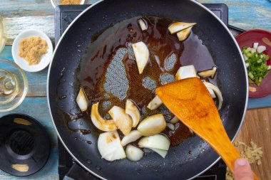 Şef tavada soğan kızartıyor.