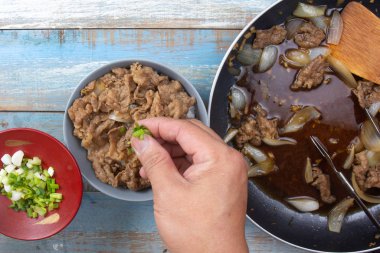 Şef pirinçli bifteğe bir dilim soğan koydu.