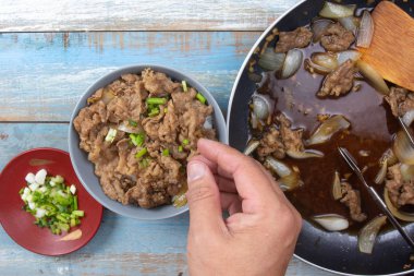 Şef pirinçli bifteğe bir dilim soğan koydu.